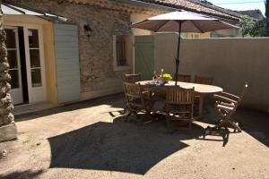 a table and chairs with an umbrella on a patio at Gîte La Charlette in Cheval-Blanc