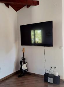 a flat screen tv hanging on a wall with a guitar at House Tena in Zaton