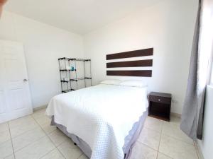 Casa Perla ¡Clima y Comfort! في El Rosario: غرفة نوم مع سرير أبيض مع اللوح الأمامي الأسود والأبيض
