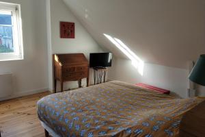 a bedroom with a bed and a desk and a television at LAtelier de la Rivière in Belle-Isle-en-Terre