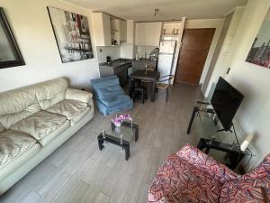 ein Wohnzimmer mit einem Sofa und einem Tisch sowie eine Küche in der Unterkunft Bella Lombarda in San Pedro de la Paz
