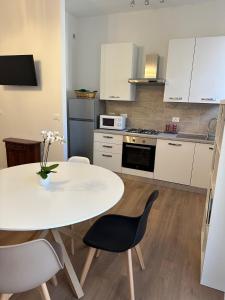 a white kitchen with a white table and chairs at Casa Marilù in Bologna