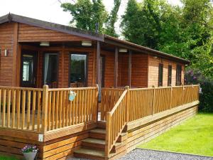 a wooden cabin with a porch and a deck at Roe Deer Lodge in Newton Stewart
