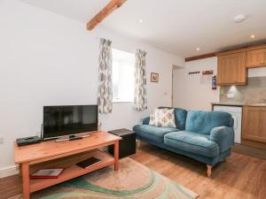 a living room with a blue couch and a tv at Ash Tree Cottage in Cowbridge
