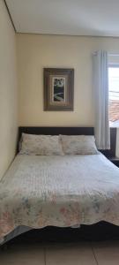 貝洛奧里藏特的住宿－Kitinet Central，一间卧室配有一张带花卉床罩的大床