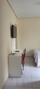 a room with a desk with a tv and a bed at Kitinet Central in Belo Horizonte