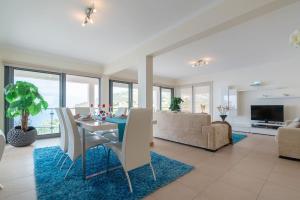 a dining room and living room with a table and chairs at Belo Mar in Arco da Calheta
