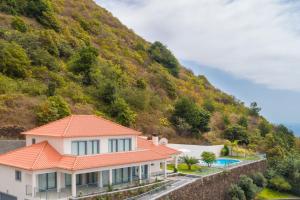 a house with an orange roof and a mountain at Belo Mar in Arco da Calheta