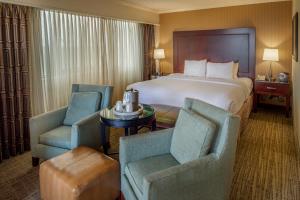 ブリッジトンにあるCrowne Plaza Hotel St. Louis Airport, an IHG Hotelのベッド1台と椅子2脚が備わるホテルルームです。