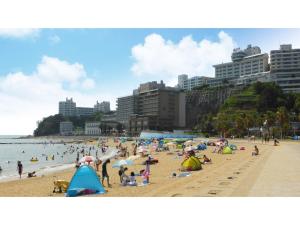 un grupo de personas en una playa con sombrillas en Nishiura Grand Hotel Kikkei - Vacation STAY 85448v en Gamagori