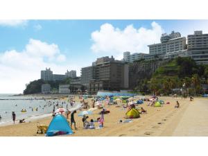 a group of people on a beach with umbrellas at Nishiura Grand Hotel Kikkei - Vacation STAY 85446v in Gamagori