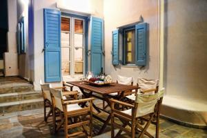 a dining room with blue shutters and a wooden table and chairs at Galini Villa in Agrari