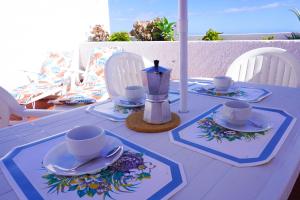 ein weißer Tisch mit Tassen und Untertassen darauf in der Unterkunft Caletillas Sun & Sea in Araya