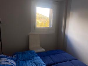 a bedroom with a blue bed and a window at Tonale 5 min Dagli Impianti Da Sci in Passo del Tonale