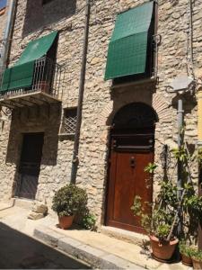 a stone building with a brown door and a green roof at A Casa da Paola in Caccamo