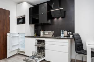 une cuisine avec des placards blancs et un mur noir dans l'établissement Apart D&K Free Parking Cybernetyki 2E, à Varsovie
