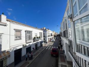 een straat met witte gebouwen en mensen die over een straat lopen bij Piso deluxe en pleno centro - San Juan 39 in Sanlúcar de Barrameda