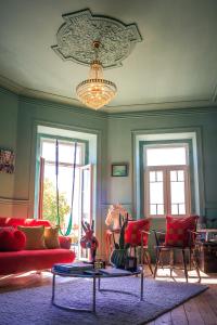 Coruche - A casa do Baloiço في كوروش: غرفة معيشة بها أريكة حمراء وثريا