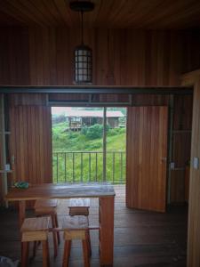 una mesa de madera y sillas en una habitación con una ventana grande en Brisa de la montaña:Cabaña con vista al bosque de Platanillo y al mar, en Platanillo
