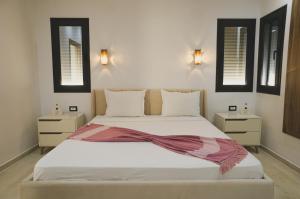 um quarto com uma cama branca com um cachecol em Villa des deux oliviers Djerba em Djerba
