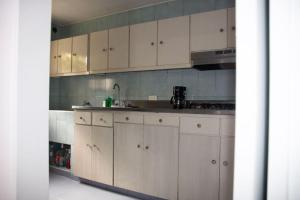una cocina con armarios blancos y fregadero en Aparta estudio acogedor, ubicación Chipichape, en Cali