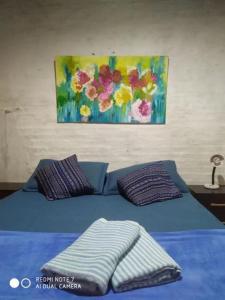 una cama azul con almohadas y una pintura en la pared en Buena Vista, en Salto