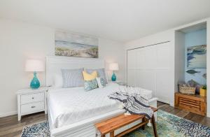 Un dormitorio con una cama blanca con almohadas azules y amarillas en Bluewater Breeze en Satellite Beach