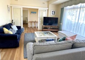 sala de estar con 2 sofás y TV de pantalla plana en Baywater, en Kingscote