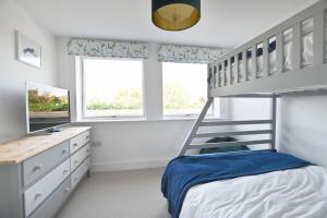 a white bedroom with a bunk bed and a desk at The Old Cottage Bakery in Lyme Regis