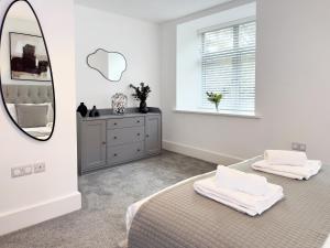 a white bedroom with two beds and a mirror at The Yorkshire Hosts - The Water Mill in Haworth