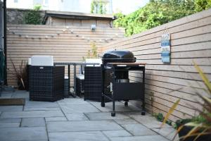 een grill op een patio naast een muur bij The Old Cottage Bakery in Lyme Regis