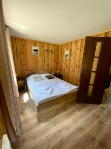 een slaapkamer met een bed en een houten vloer bij Domek w górach na wyłączność Karkonosze in Mniszków