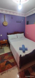 1 dormitorio con 1 cama grande y paredes moradas en Casa Lotfi, en Chefchaouen