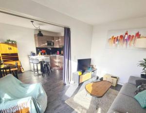 a living room with a couch and a table and a kitchen at Appartement à 20mn de Paris et 40mn de Disney in Fontenay-sous-Bois