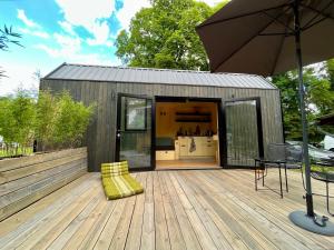 a small building with an umbrella on a wooden deck at Tiny House zwischen Berlin und Potsdam in Berlin