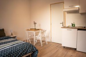 a room with a bed and a table and a kitchen at TC Residences - Charmant Appartement in Saint-Quentin