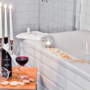 una botella de vino y una copa de vino tinto junto a la bañera en Hotel & Restaurant Utspann Schafflund, en Schafflund