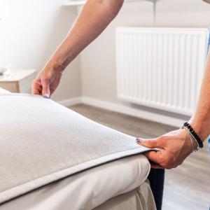 una persona sta mettendo una coperta su un letto di Hotel garni Utspann Schafflund a Schafflund 1 altra foto