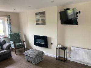 sala de estar con TV, sofá y silla en McConaghys Glenside Farmhouse Whitepark Bay, en Ballintoy