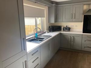 uma cozinha com armários brancos, um lavatório e uma janela em McConaghys Glenside Farmhouse Whitepark Bay em Ballintoy