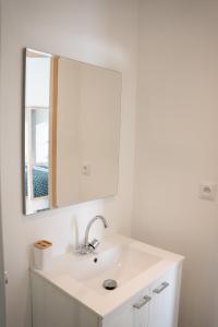 een witte badkamer met een wastafel en een spiegel bij TC Residences - Charmant Appartement in Saint-Quentin