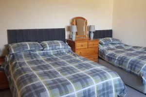 a bedroom with two beds and a dresser and a mirror at McConaghys Glenside Farmhouse Whitepark Bay in Ballintoy