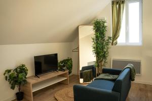 een woonkamer met een blauwe bank en een tv bij TC Residences - Charmant Appartement in Saint-Quentin