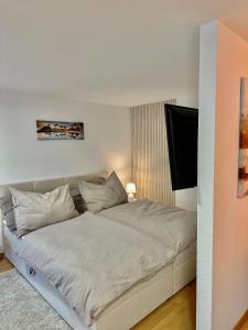 un letto con lenzuola e cuscini bianchi in una camera da letto di Ferienwohnung zwischen Hafen und Stadt a Bregenz