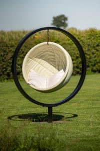 un miroir circulaire avec une balançoire dans l'herbe, dans l'établissement Ter Heyde Walle, à Koekelare