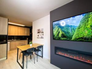 Il comprend une cuisine avec une table et une télévision murale. dans l'établissement Espectacular Apartamento Con Vistas En Escaldes - 10min Caminando Al Centro - Parking Gratis, à Escaldes-Engordany