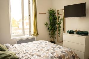 a bedroom with a bed and a tv and a plant at TC Residences - Charmant Appartement in Saint-Quentin