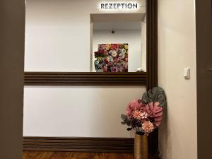 a mirror on a wall with a vase of flowers at Hotel Unterfeldhaus in Erkrath