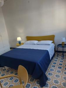 um quarto com uma cama azul com duas mesas e uma cadeira em Una Rosa Blu em Valderice