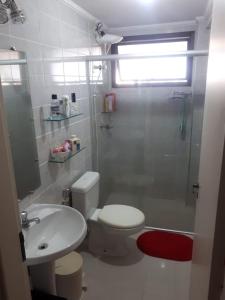 uma casa de banho com um WC, um chuveiro e um lavatório. em Apto Enseada Coral Gables no Guarujá